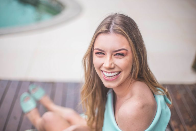A woman sits near a pool smiling