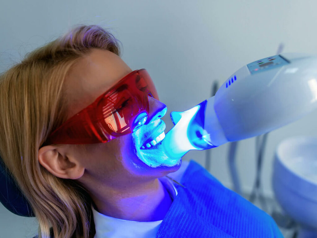 A dental patient receiving in-office teeth whitening using a laser