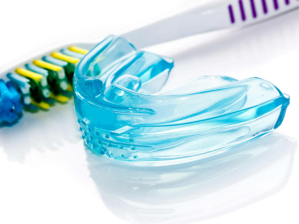 blue mouthguard laying next to a toothbrush