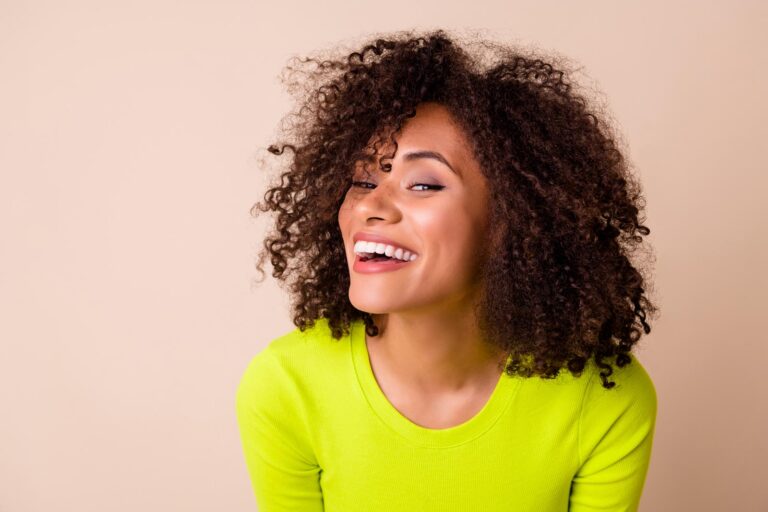 Smiling woman showing bright, even teeth enhanced with dental veneers for a natural-looking smile makeover.